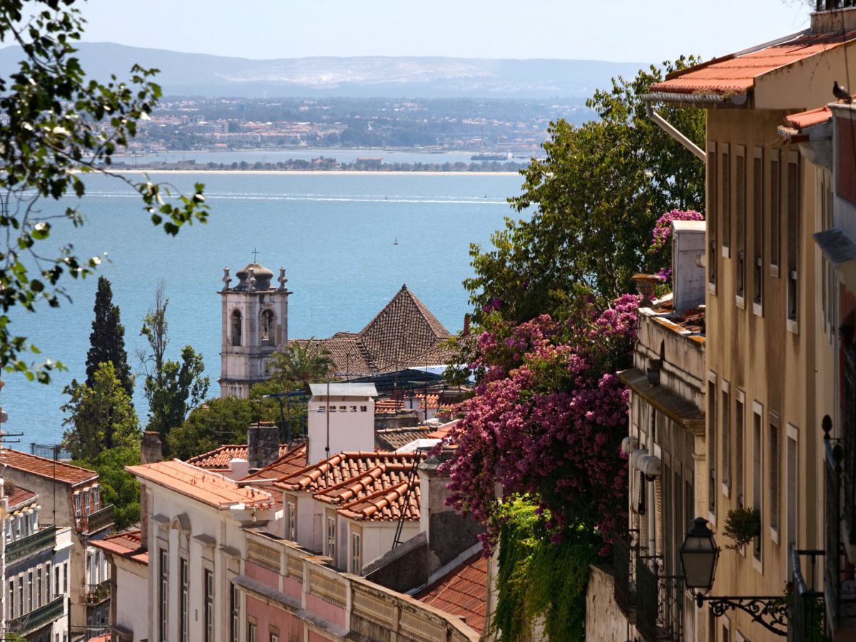 Verwinkelte Gassen in Lissabon, im Hintergrund das Meer.