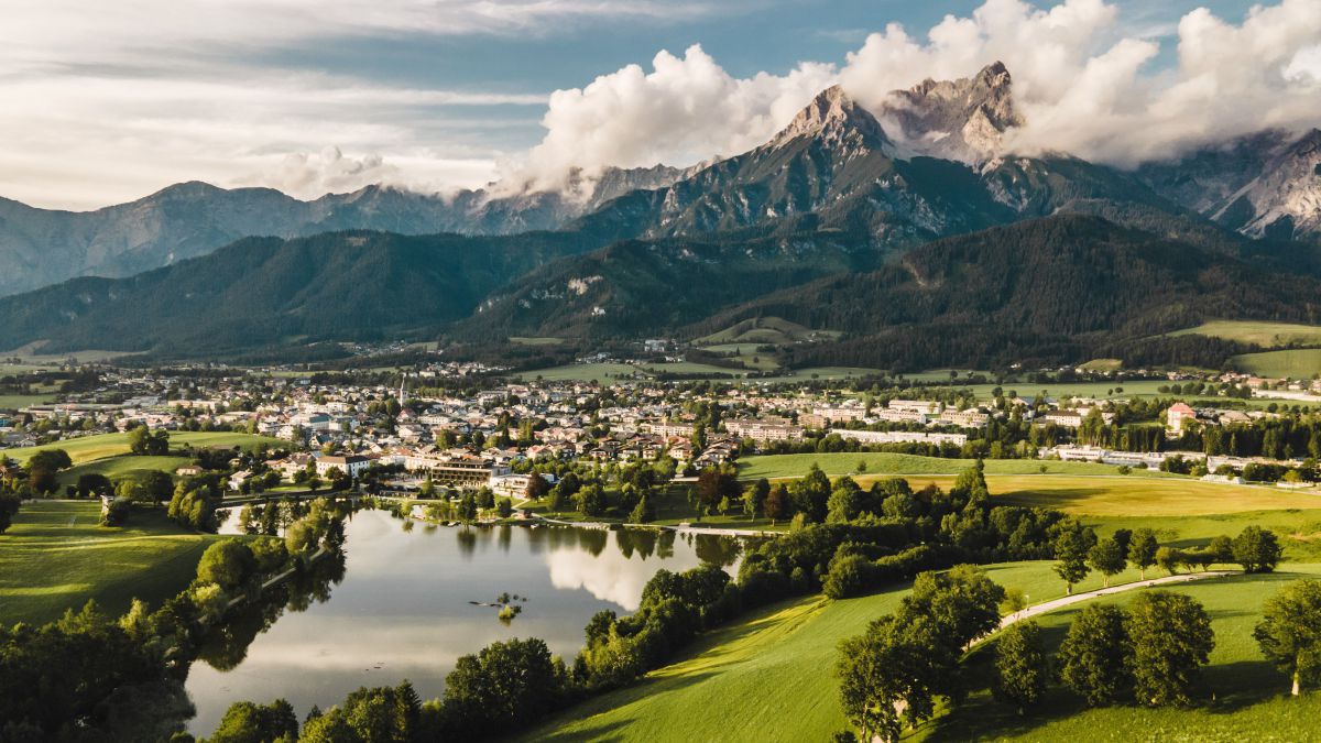 Panoramablick über den Ritzensee auf Saalfelden, dahinter mächtige Berge.