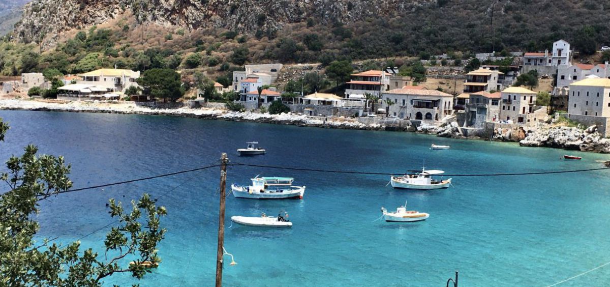 Boote schweben scheinbar auf der klaren türkisblauen Wasserfläche einer Bucht auf der griechischen Halbinsel Mani.