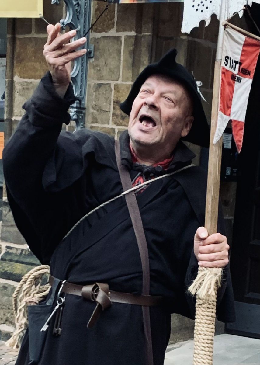 Ulrich Dammer in seiner Rolle als mittelalterlicher Nachtwächter, entsprechend gekleidet in dunkler Kutte, schwarzem Dreispitz-Hut und einem großen Schlüsselbund am Gürtel.