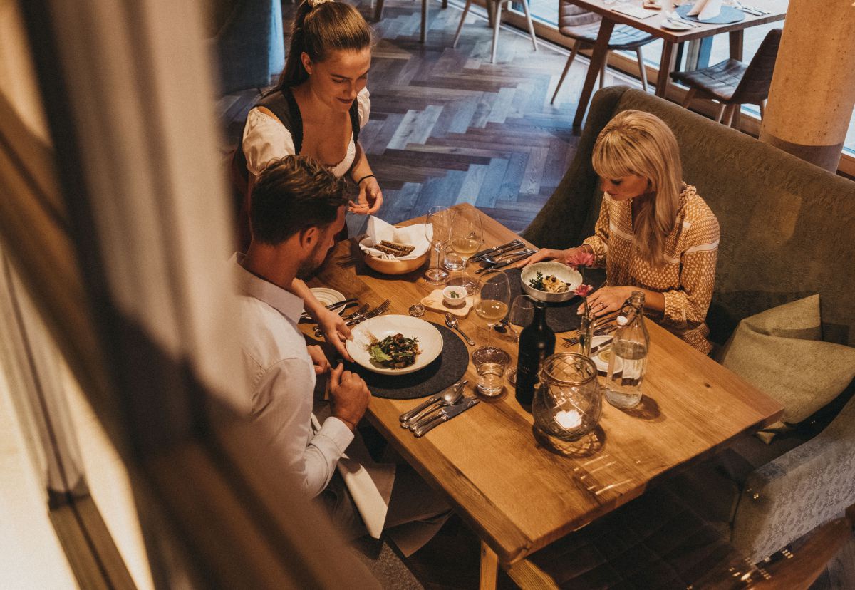 Mann und Frau beim Abendessen, Kellnerin ist gerade beim Tisch, Aufnahme von oben.