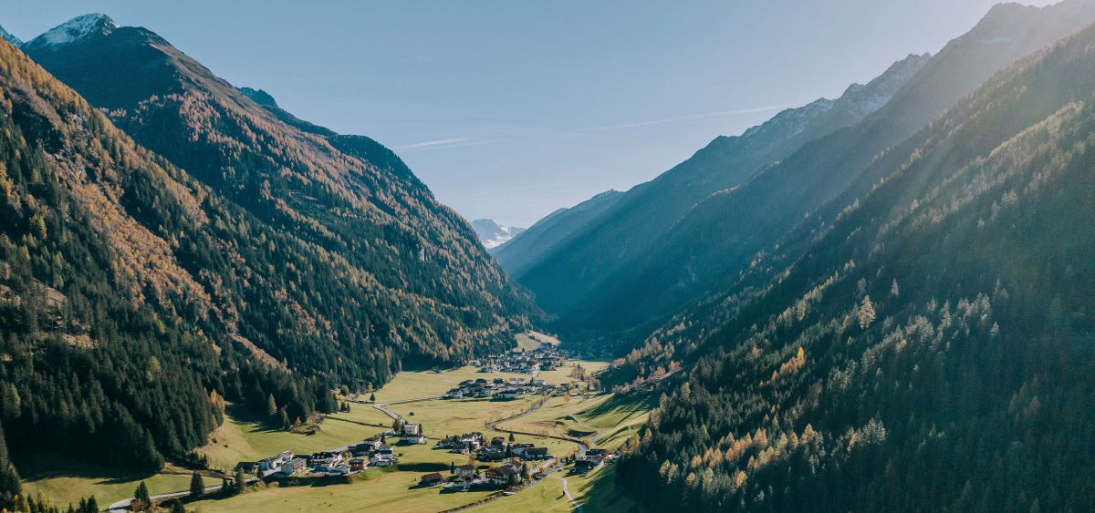 Bergtal, grüne Wiese, eine Straße, einige Häuser.
