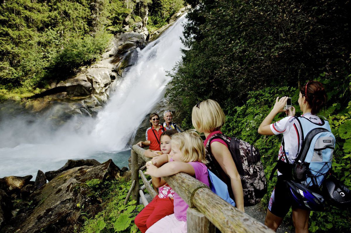 Eine Familie aus 3 Generationen auf einem gesicherten Wanderweg mit Blick auf den Wasserfall.