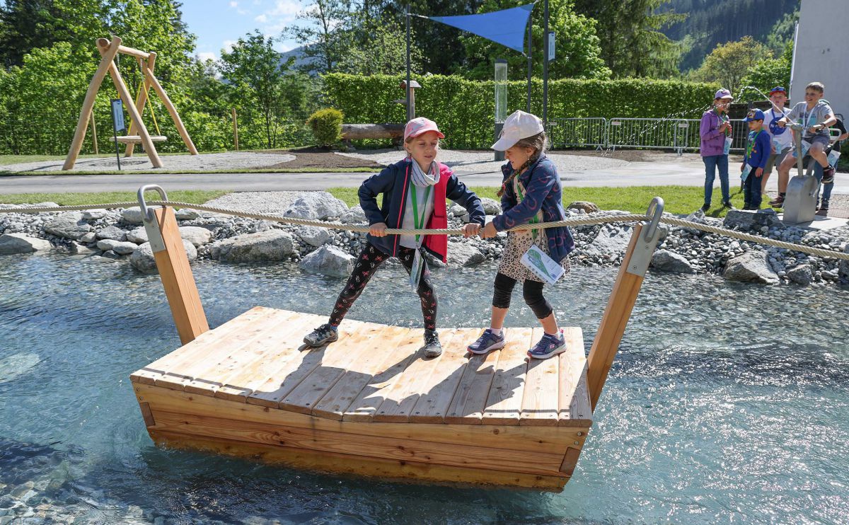 2 Kinder ziehen sich auf einem Floß ein Seil entlang.