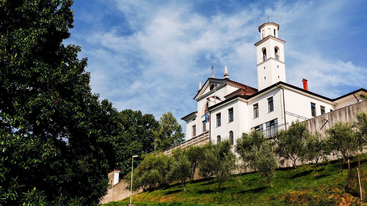 Weißes Kirchengebäude auf einer Anhöhe.