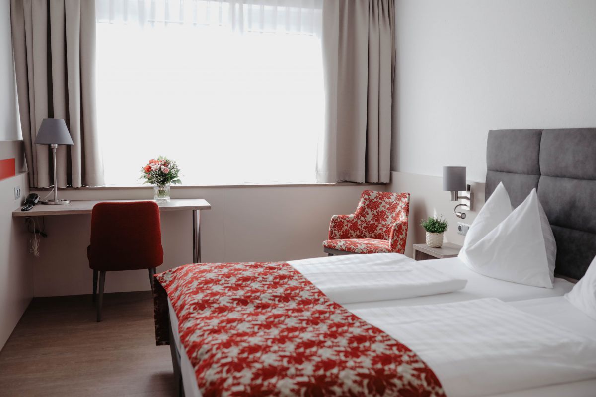 Blick in ein Zimmer mit Doppelbett und Schreibtisch.