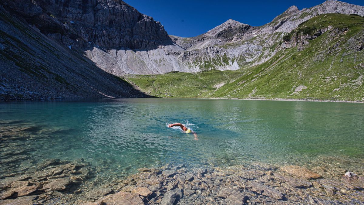 Mann schwimmt in einem Bergsee.