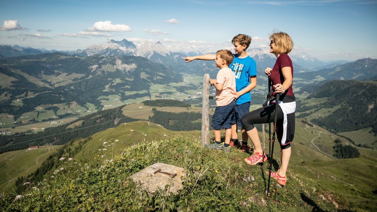 Frau mit 2 Kindern auf einem Aussichtspunkt mit Blick ins Tal.