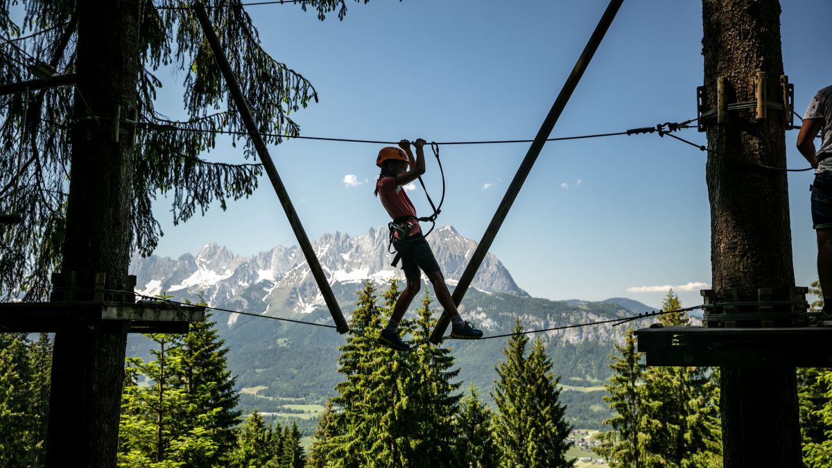 Mädchen im Klettergarten. Im Hintergrund majestätisch der Wilde Kaiser