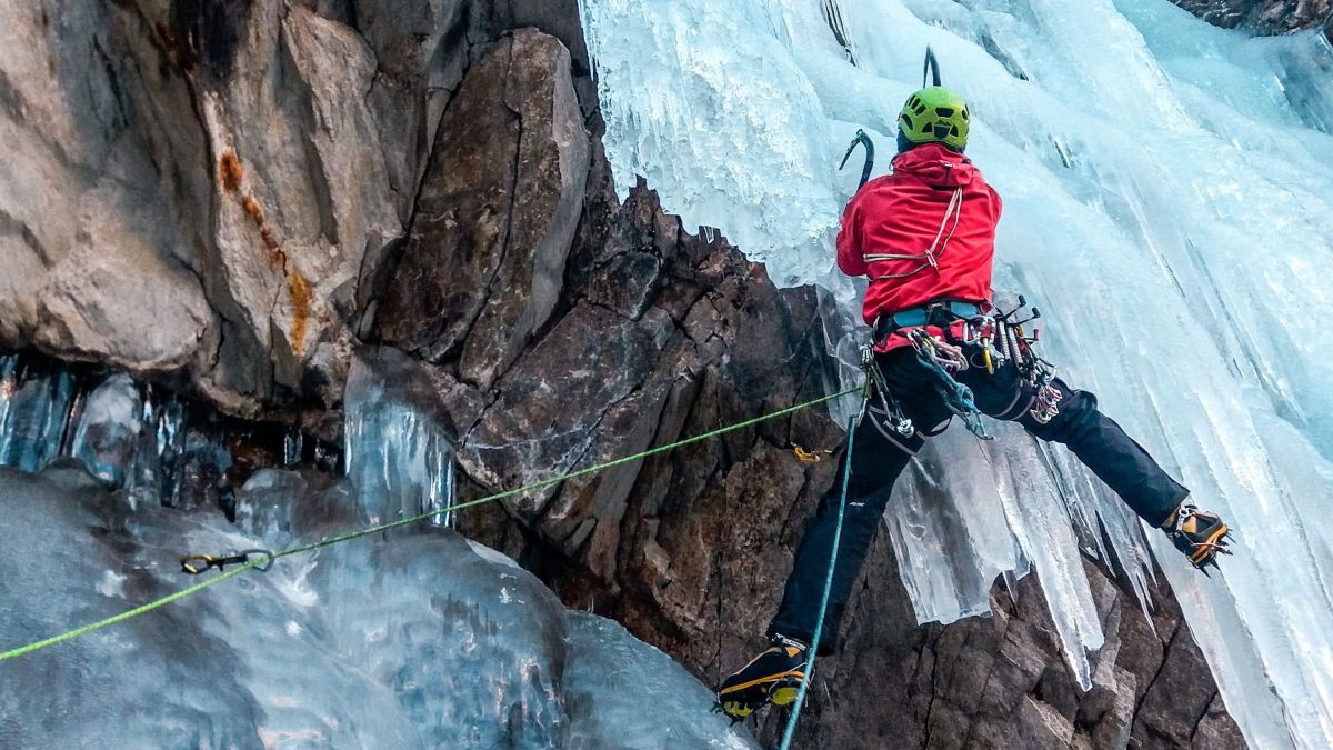 Person klettert einen gefrorenen Wasserfall hoch.
