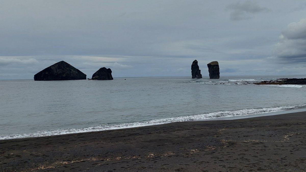 Strand, 4 Felsen, der Himmel ist bedeckt.