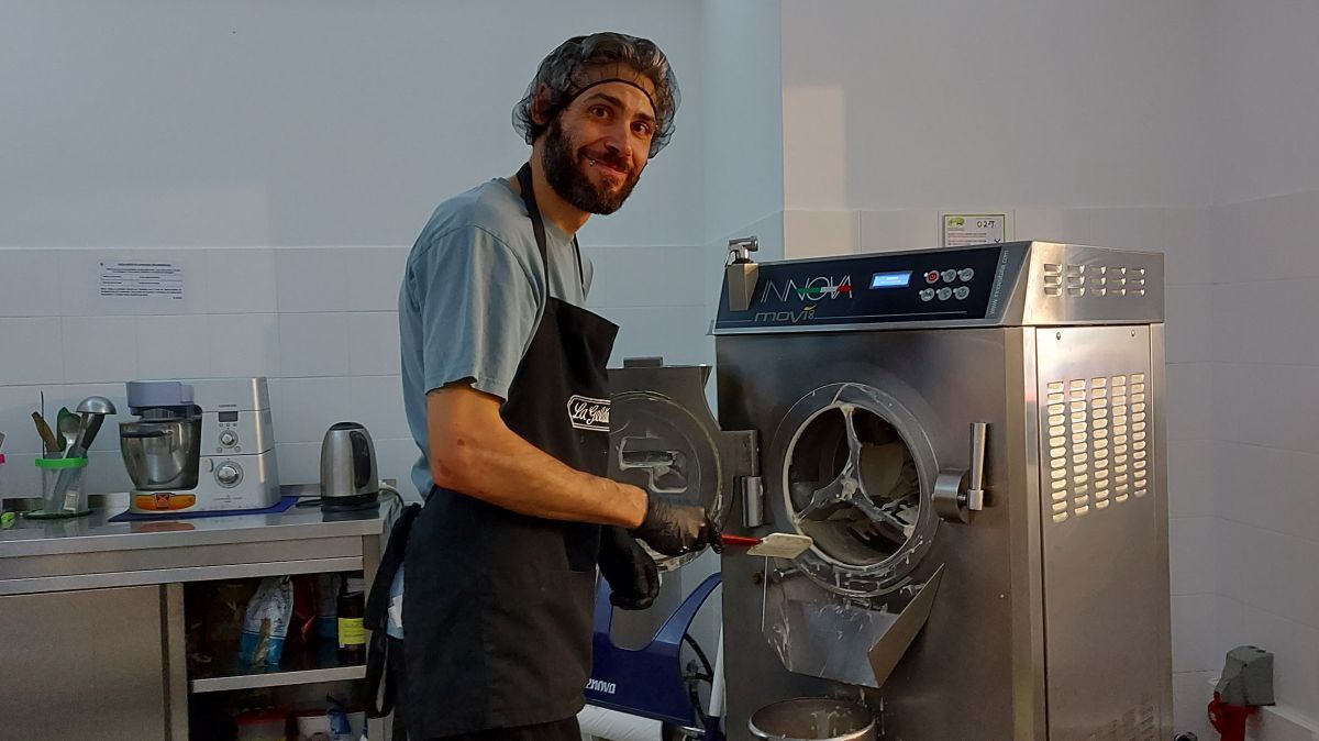 Davide mit Plastikhaube über seinen Haaren vor seiner Eismaschine.