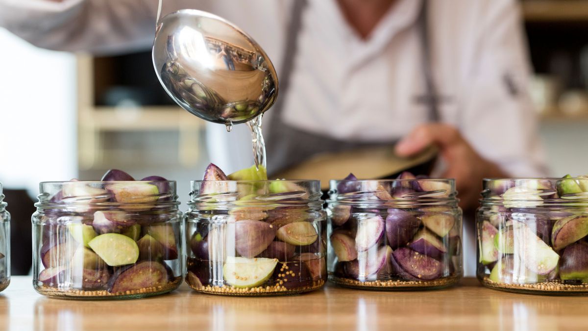 Person befüllt Gläser mit Obst-