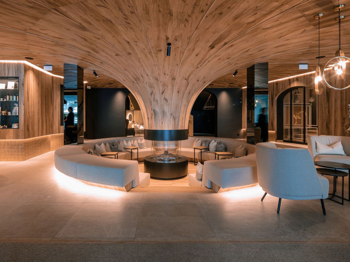 Trichterförmige Säule aus Holz, rundherum Sitzgelegenheiten.