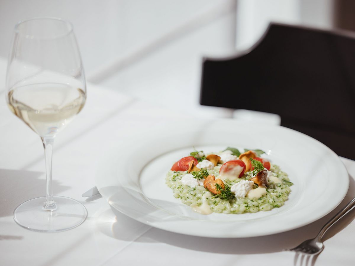 Teller mit Risotto und Tomaten, dazu ein Glas Wein.