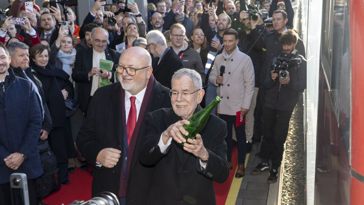 Viele Menschen am Bahnsteig, im Vordergrund Herr Matthä und der Bundespräsident, der eine Flasche Richtung Zug wirft.