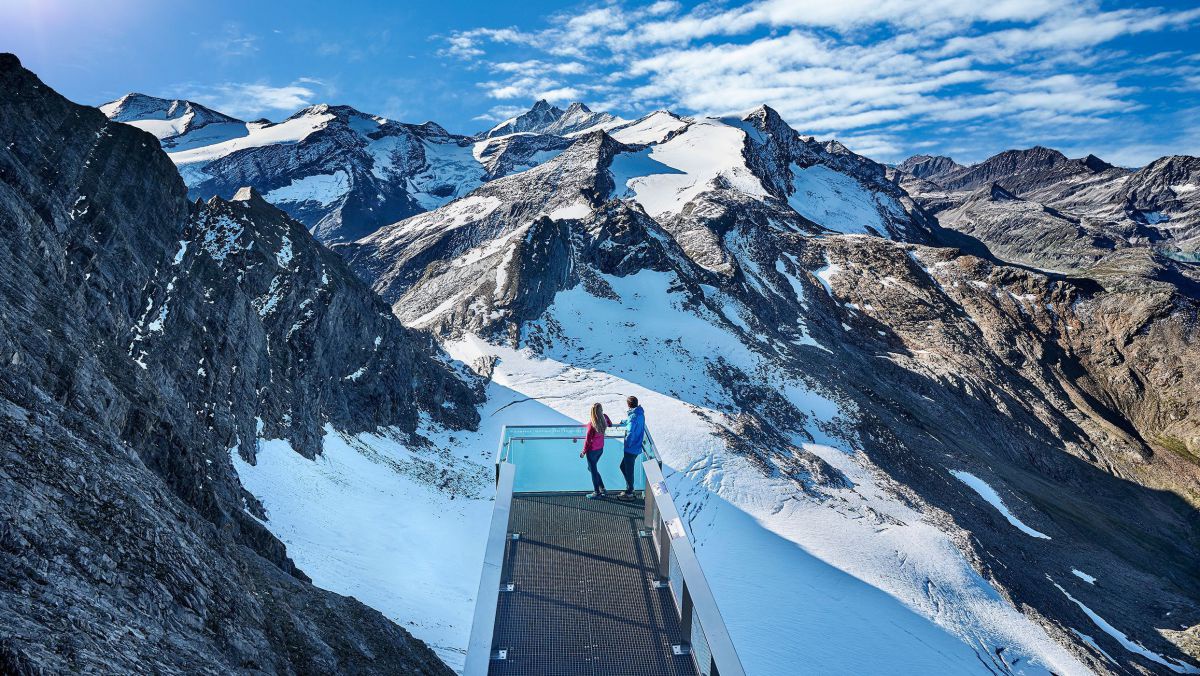 2 Personen auf einer Aussichtsplattform. Der Blick geht Richtung Gletscher.