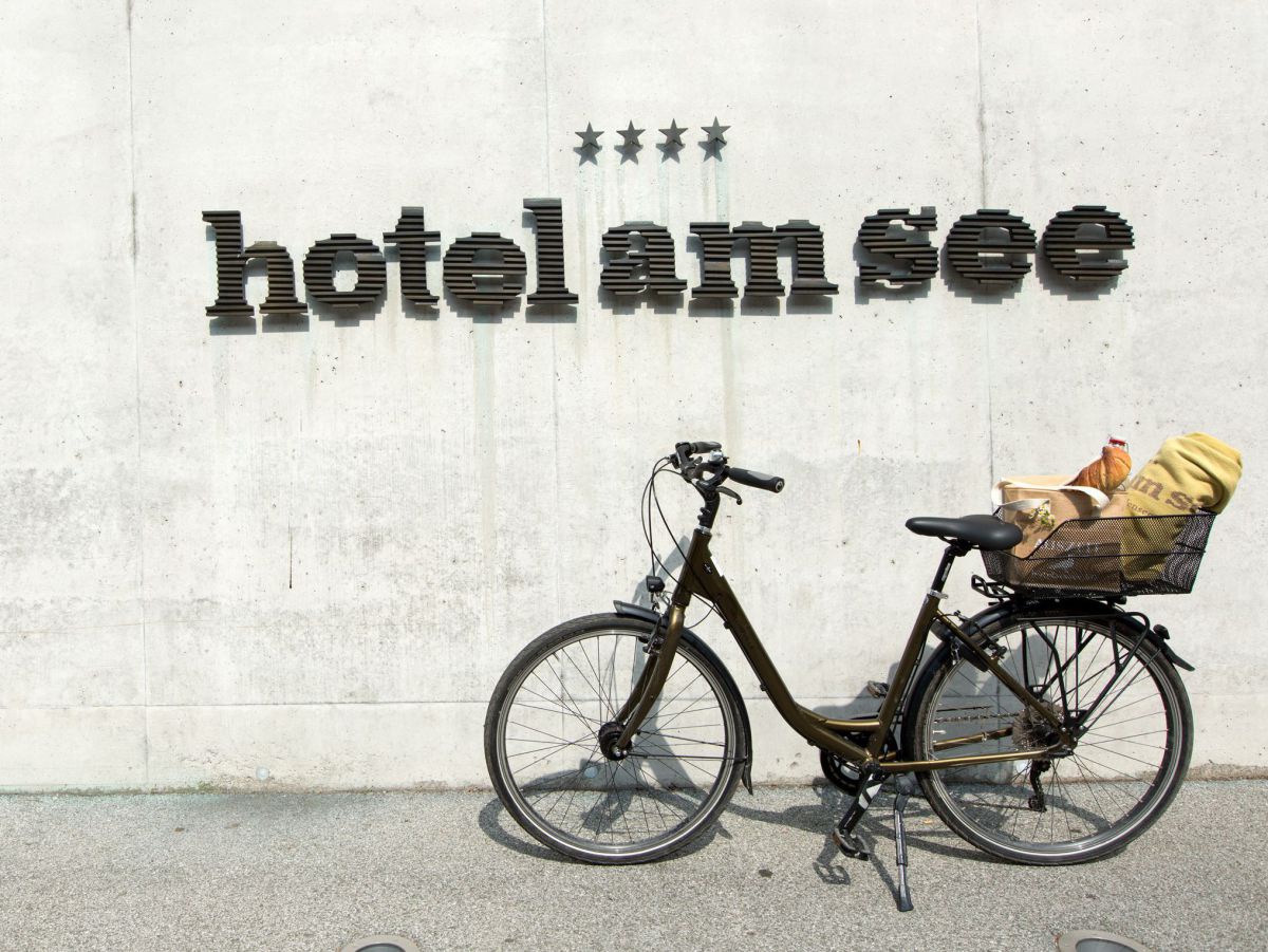 Fahhrad angelehnt an die Hotelwand mit Schriftzug ****Hotel am See, hinten am Rad ein Picknickkorb.