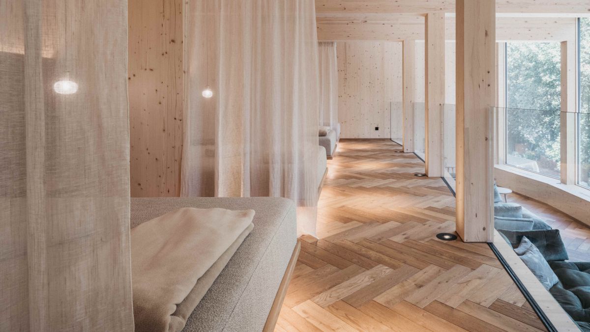 Ruheraum mit Doppelliegen und Vorhängen dazwischen. Viel helles Holz.