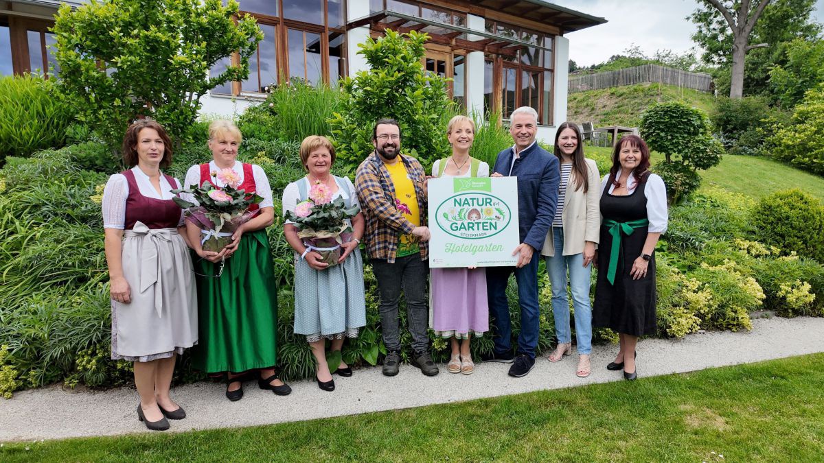 Gruppe von 8 Personen im Garten vor dem Hotel. Ulli und Herm,ann Retter halten die Gartenplakette.