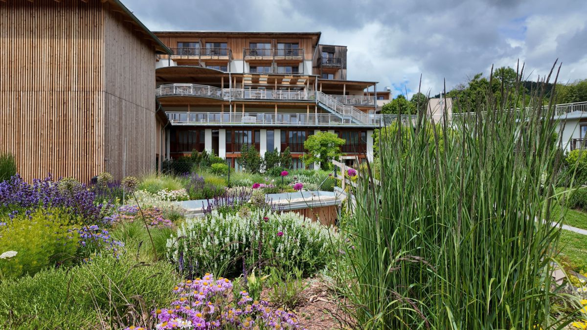 Üppig bepflanzter Garten, im Hintergrund das Hotel.