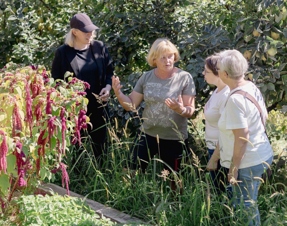 Frau führt drei andere Frauen durch den Garten.
