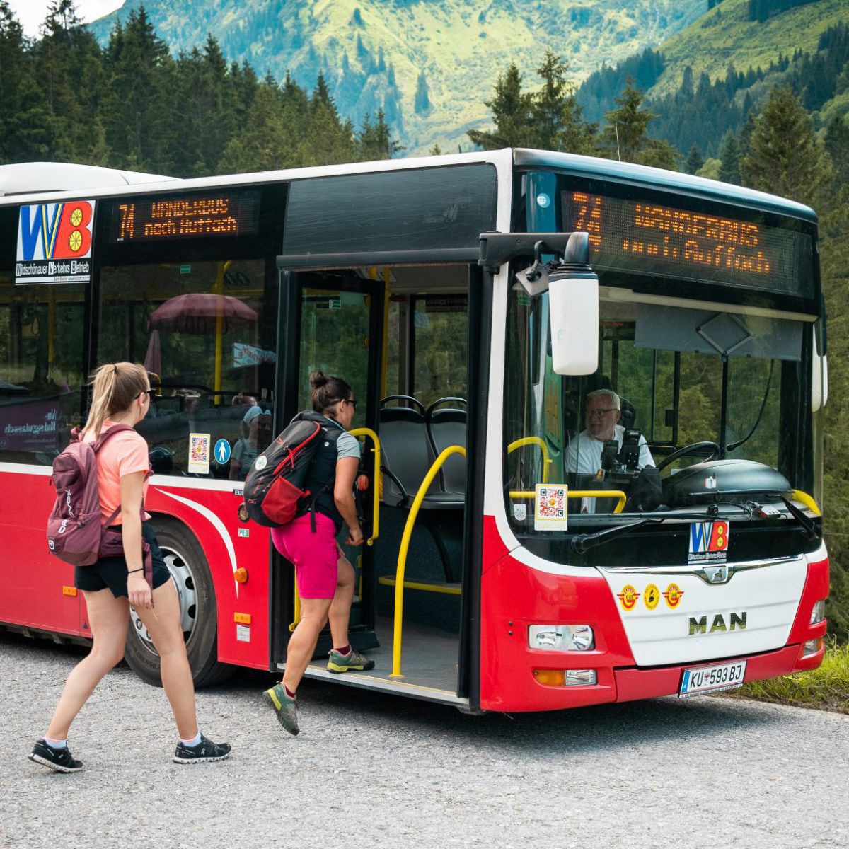 2 Frauen steigen in einen roten Bus.