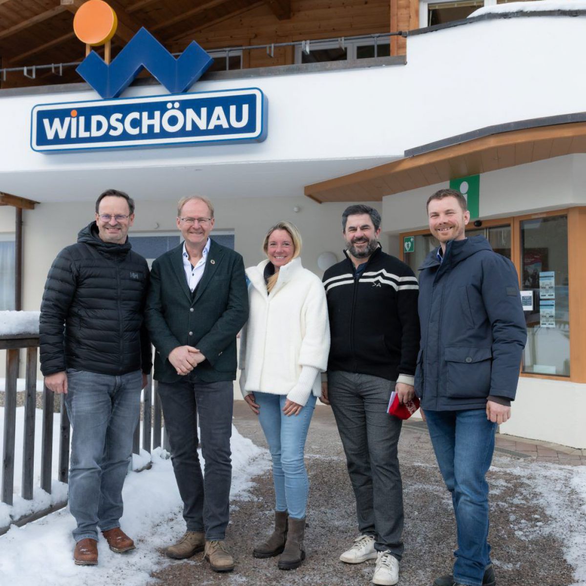 5 Personen auf einer Brücke vor einem Haus.