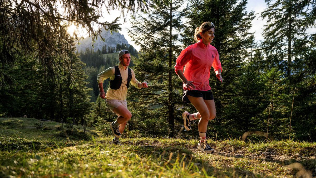 Mann und Frau laufen auf einer Waldlichtung.
