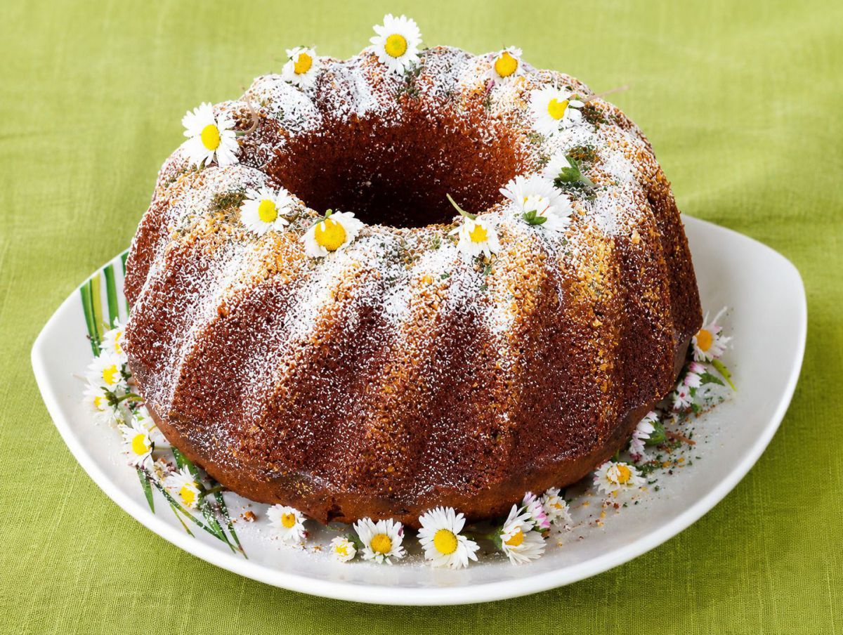 Gugelhupf auf einem Teller, rundherum mit Gänseblümchen drapiert.