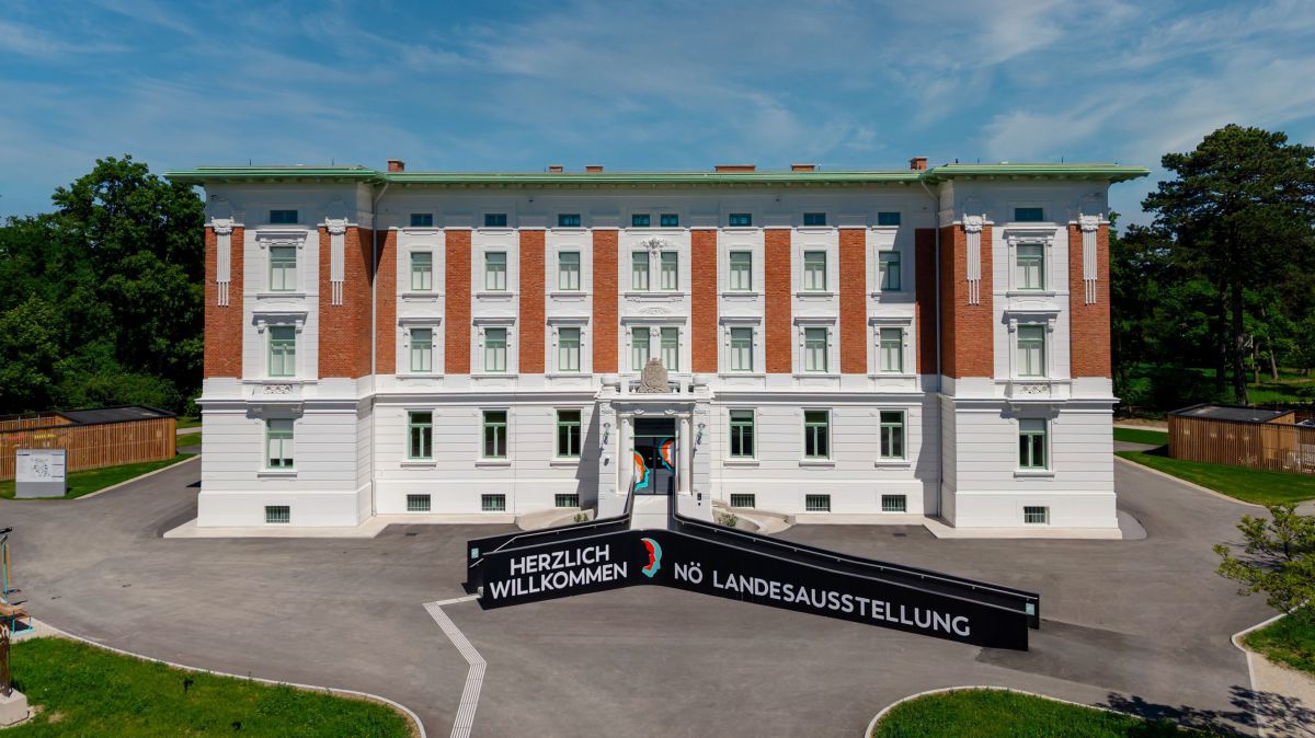 Jugensatilgebäude - weiß mit roten Ziegeln - davor winw Rampe mit der Aufschrift Herzlich Willkommen NÄ Landesausstellung