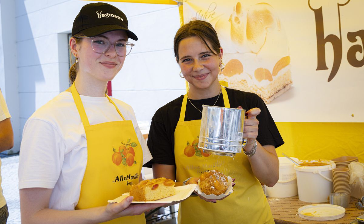 2 Mädchen halten Marillenknödel und Marillenkuchen in die Kamera.