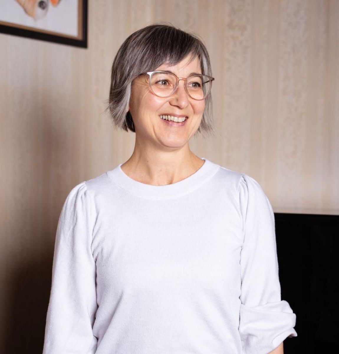 Frau Müller in weißem, langärmeligen Shirt.