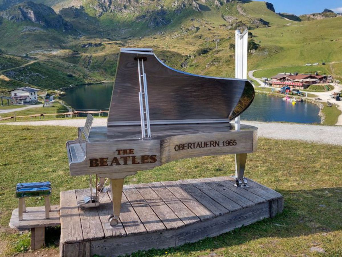 Auf einem Holzpodest steht ein hölzernes Klavier mit der Aufschrift 