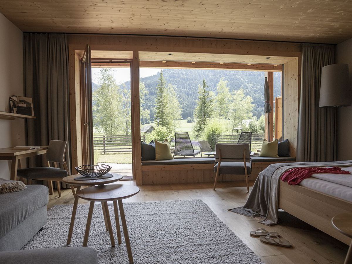 Zimmer mit viel Holz, einem großen Fenster mit Blick in die Natur.
