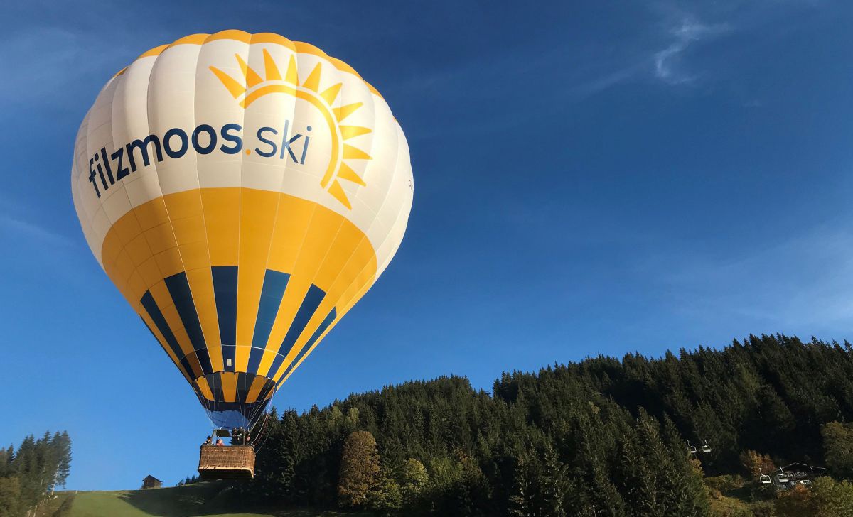 Gelber Ballon schwebr über einen Hand, dahinter strahlend blauer Himmel.