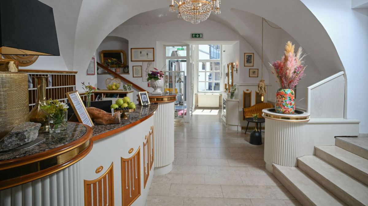 Empfangsbereich des Hotels von innen richtung Eingang hin fotografiert, links die Rezeption, rechts eine Treppe nach oben.