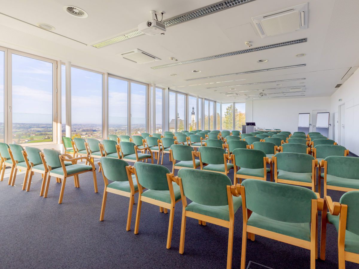 Seminarsaal mit vielen grünen Sesseln.