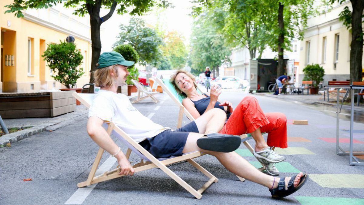 Mann und Frau chillen auf Klappstühlen auf einer Straße. 