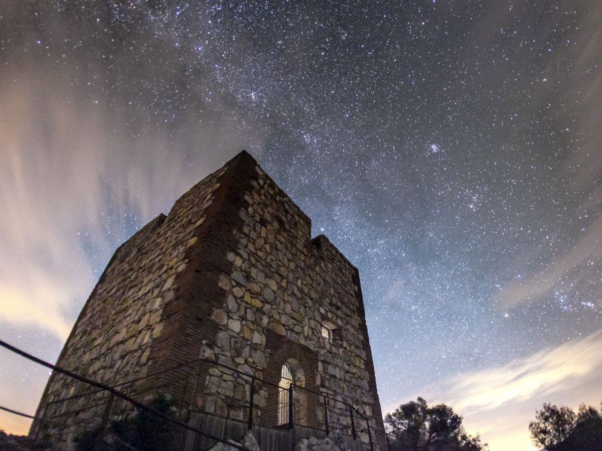 Ein mittelalterlicher Turm unter einem hellen Sternenhimmel.