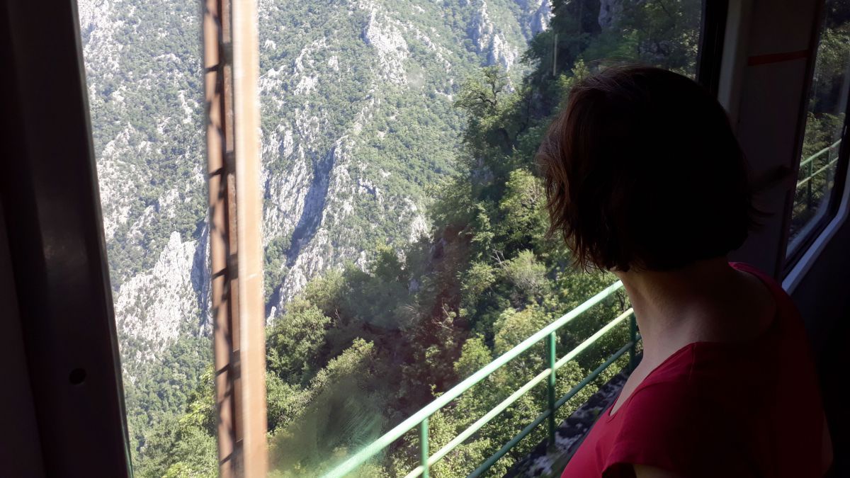 Frau blickt aus dem Zugfenster in eine Schlucht.