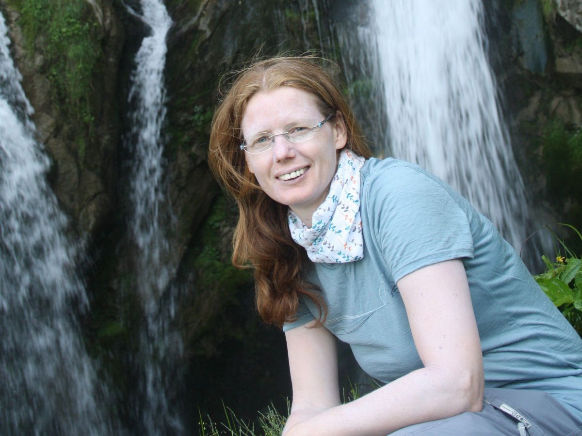 Anna Kodek hockt vor einem Wasserfall.