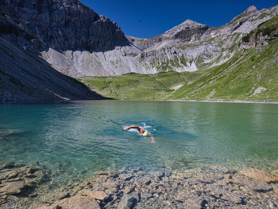 Mann schwimmt in einem Bergsee.