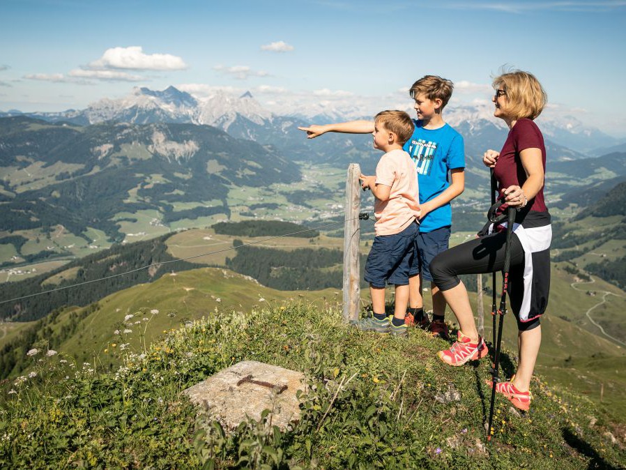 Frau mit 2 Kindern auf einem Aussichtspunkt mit Blick ins Tal.
