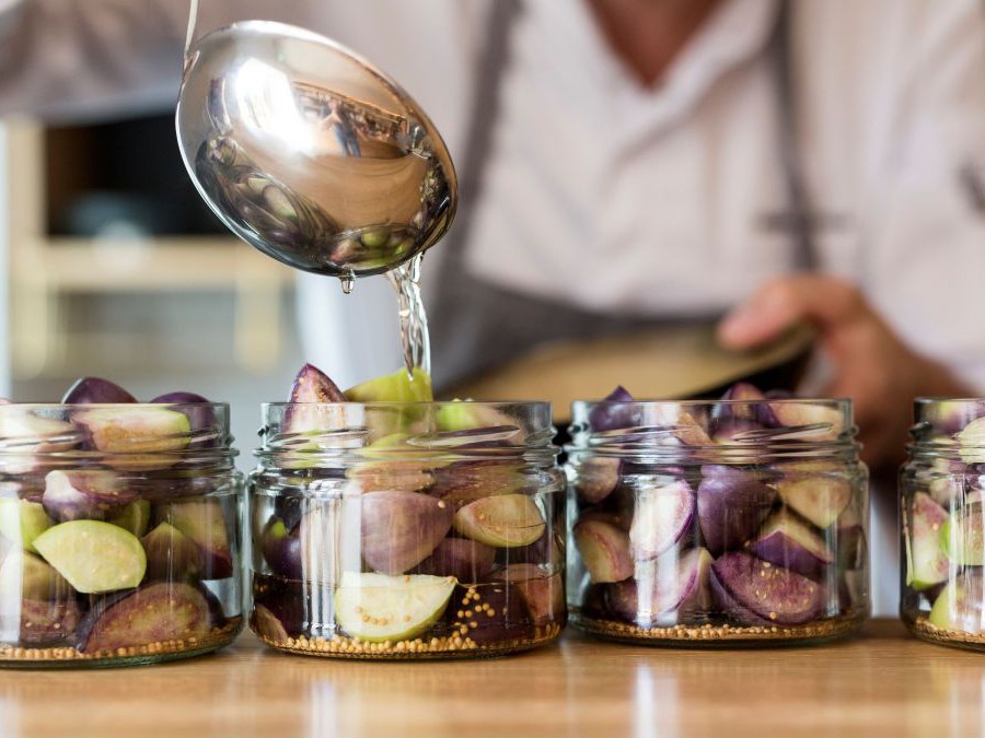 Person befüllt Gläser mit Obst-